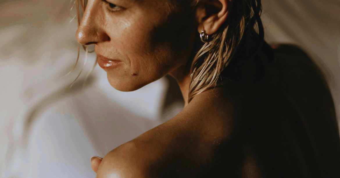 Γυναίκα κρατάει απαλά το σώμα της, συμβολίζοντας φροντίδα, αυτοπεποίθηση και σύνδεση με την υγεία της.